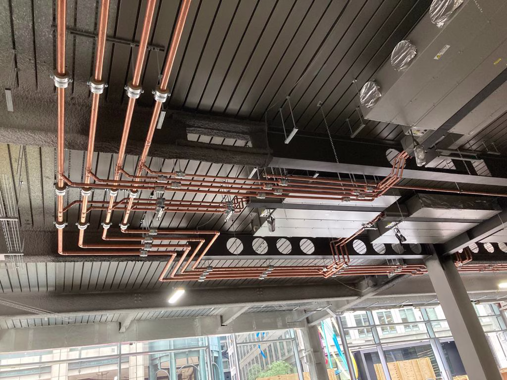 Commercial ceiling with copper heating pipes and HVAC ductwork